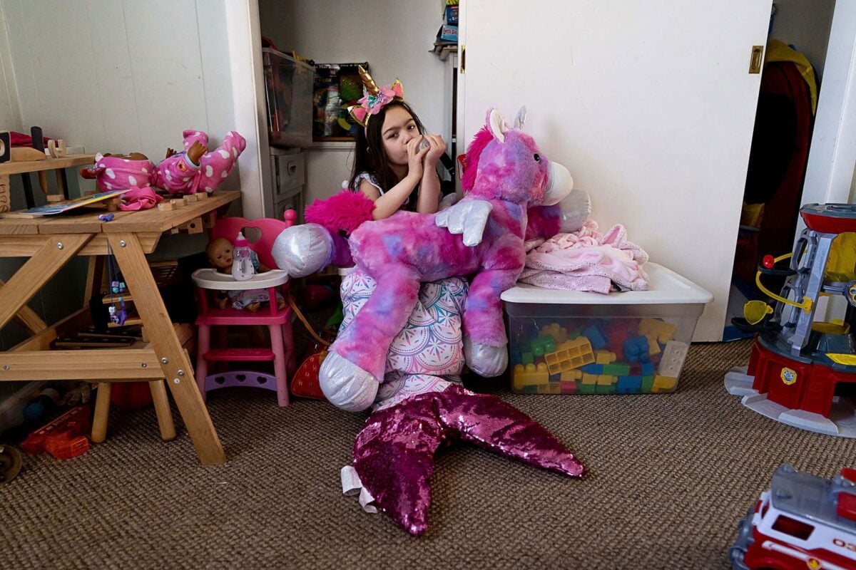 child dressed up as a mermaid holding a unicorn stuffed animal by Gabriella Hunt Photographer