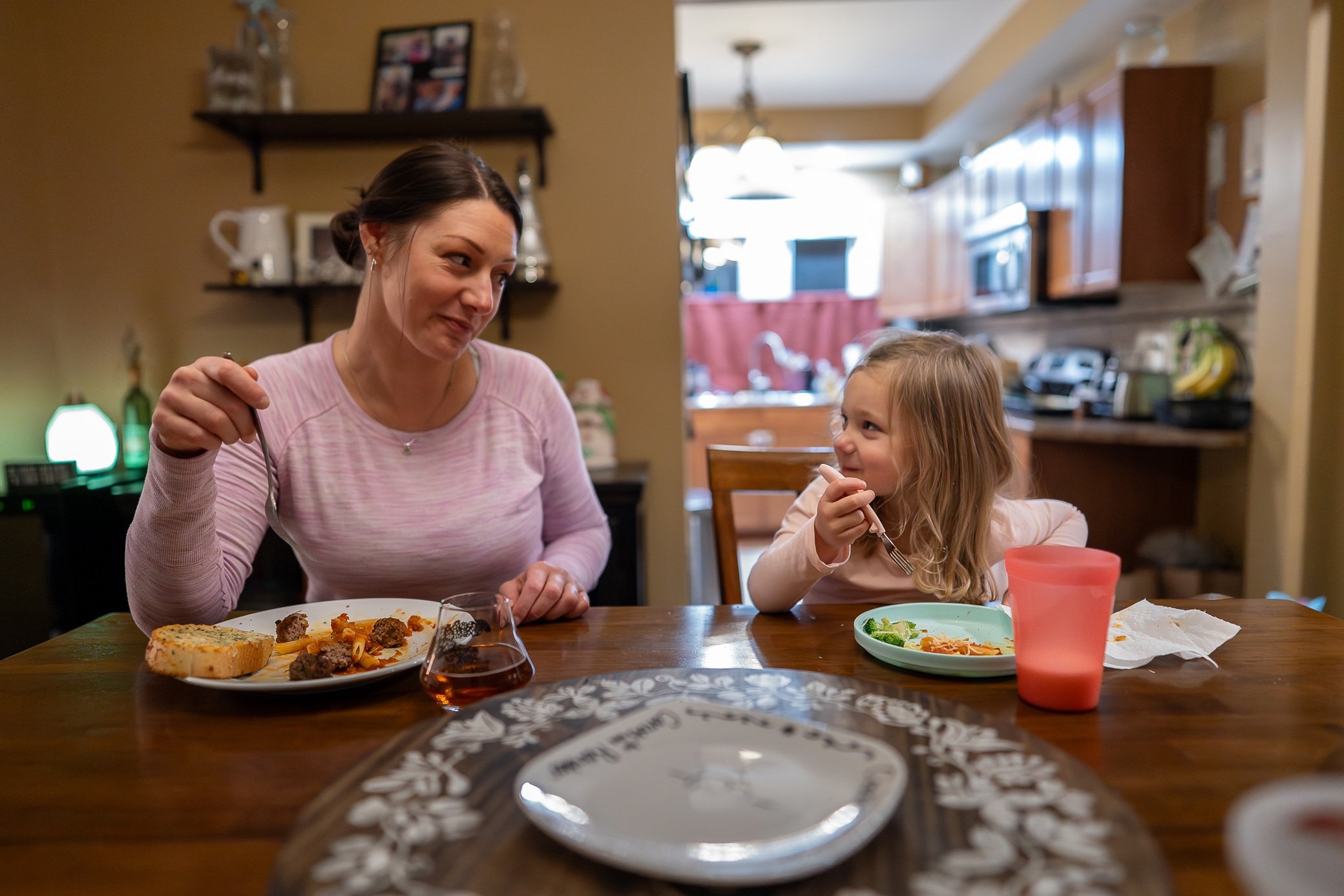 Mom and daughter eating dinner at the table and looking at each other